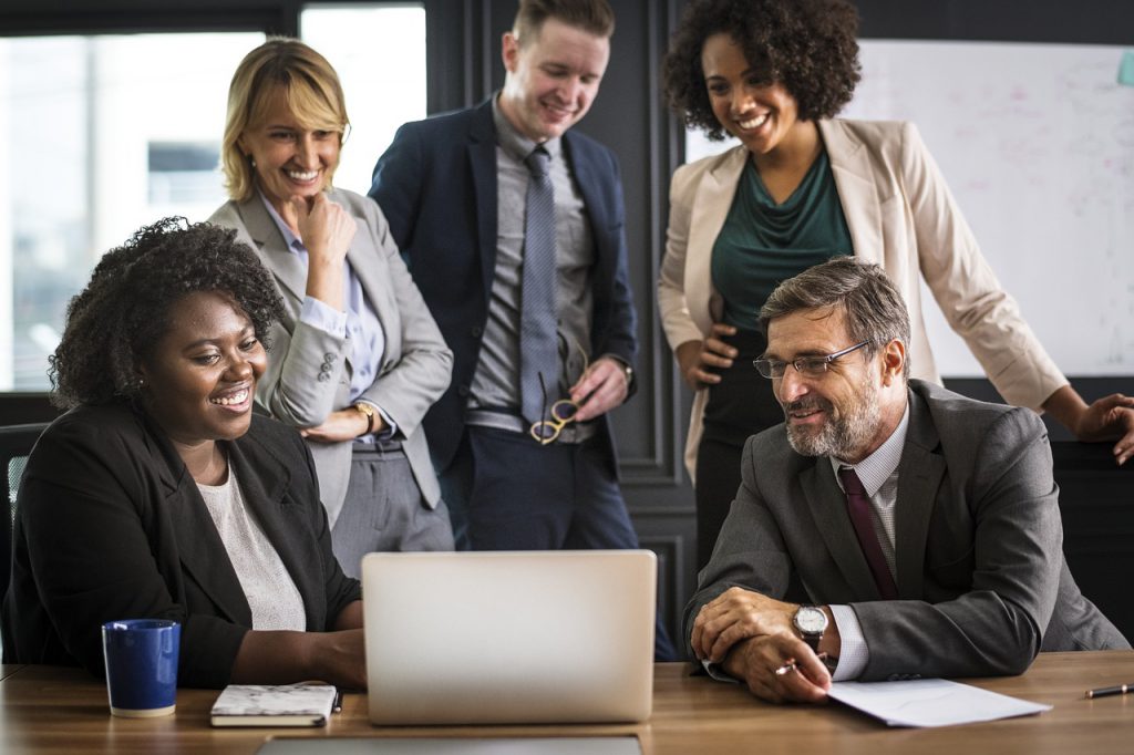 happy colleagues working together round a computer looking after employees mental health