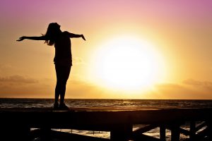 woman standing happily on a beach at dawn for a blog by Wellspace on mental resilience training