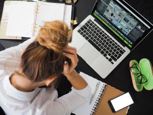 woman at her desk with her head in her hands for blog by wellspace on 7 signs you have an unhappy employee
