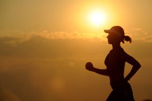 image of woman running in the sunset to represent a blog by Wellspace on exercises to do at work