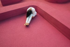 woman bend over on red floor for blig on absenteeism vs presenteeism by Wellspace