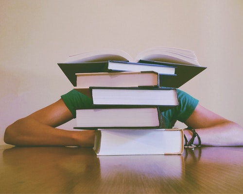 woman behind a stack of books for blog on handling stress in the workplace