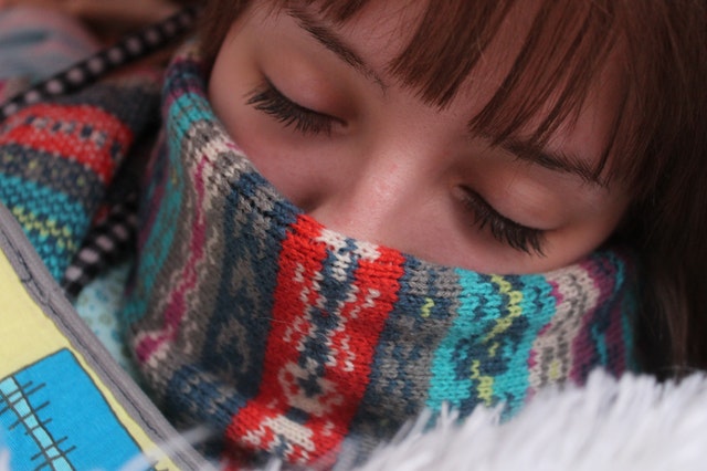 woman with scarf on her face representing blog by Wellspace on preventing office illness