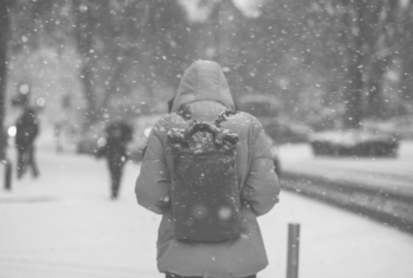 Image of person walking through snow with a backpack to represent blog bhy wellspace on keeping your staff safe in winter