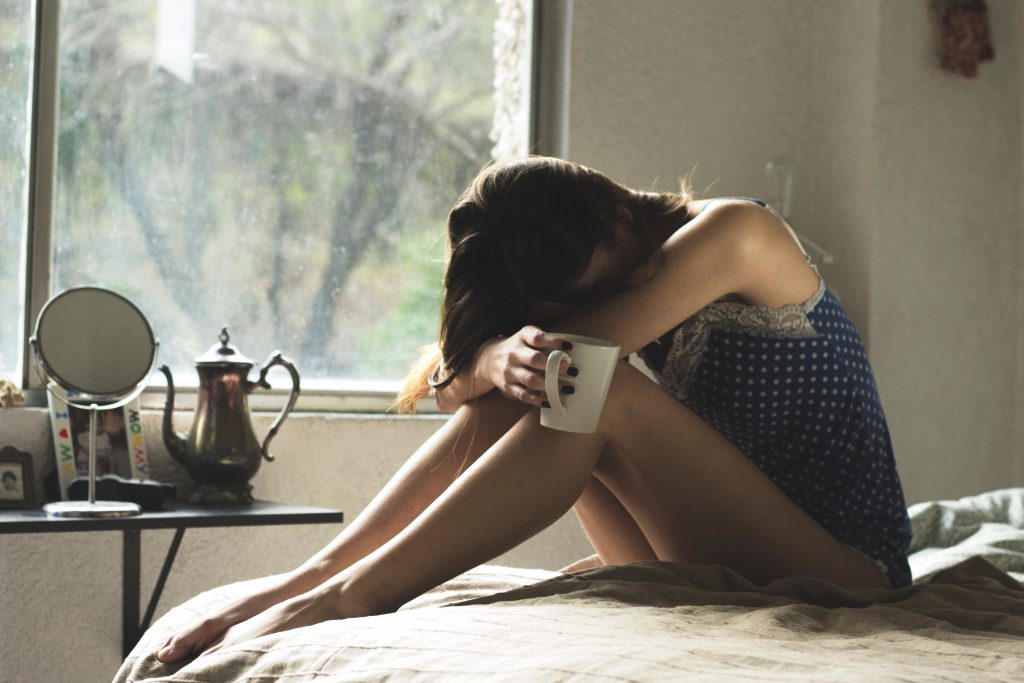 woman on a bed looking sad drinking from a mug for blog by wellspace on keeping your staff safe in winter