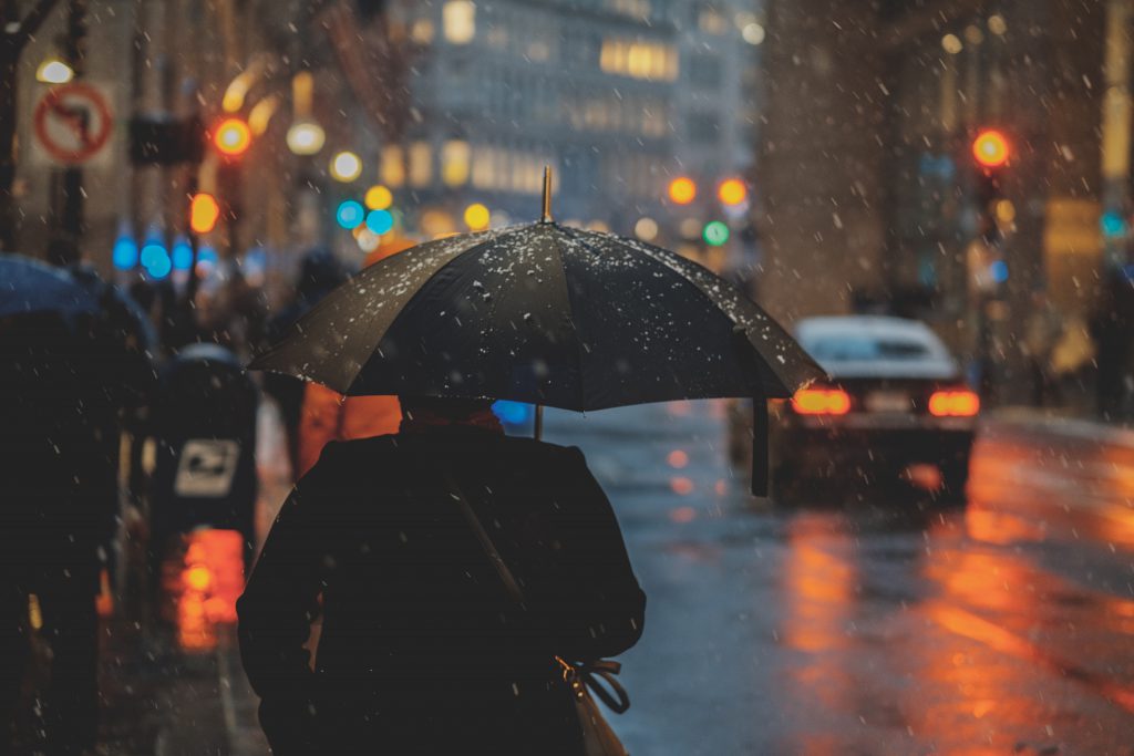 man walking down a wet road under umbrella for blog by wellspac eon keeping your staff safe in winter 