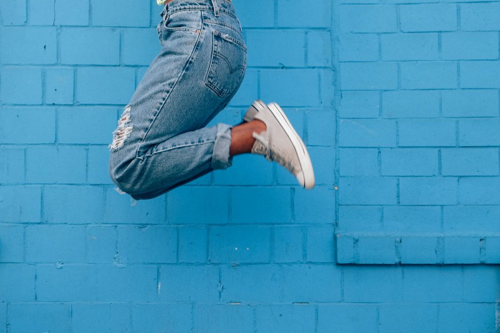 woman jumping for joy in front of a wall for happy 9-5 blog by corporate wellness experts, Wellspace