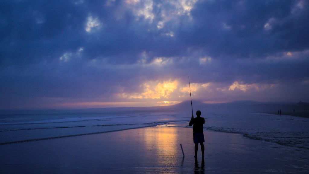 person fishing on a beach after a stressful week at work for blog by Wellspace 