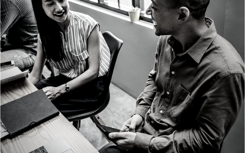 Two people sat smiling depicting dealing with workplace harassment for Wellspace blog