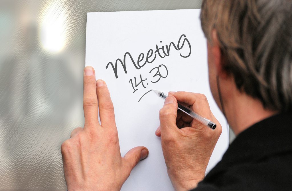 Man writing meeting time on white paper for Wellspace blog Looking After Your Workplace Wellbeing