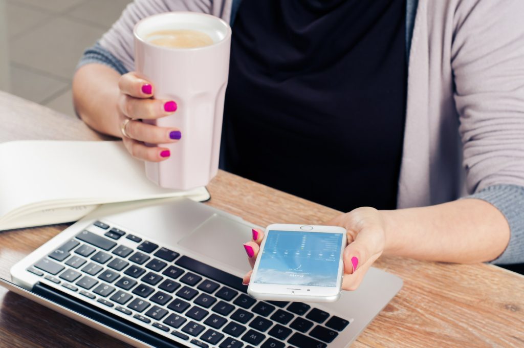 Image of young girl in an office with phone and coffee cup to illustrate blog by Wellspace on Workplace Health and Wellbeing for young people