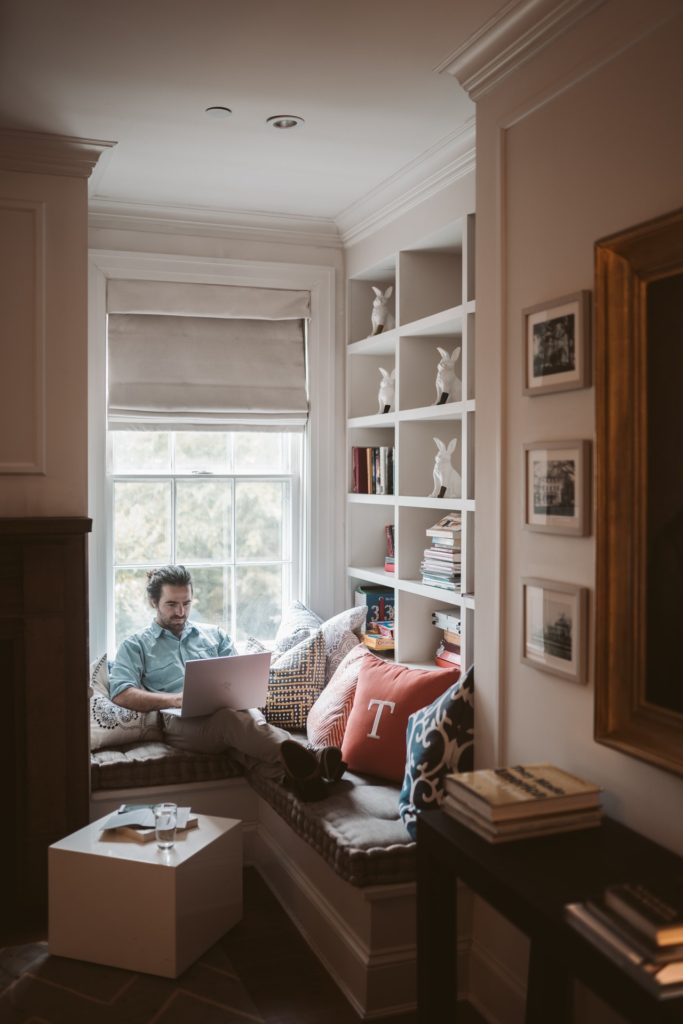 Image of a man in a window seat working from home for blog by Wellspace on Managing Employee Productivity Whilst Working from Home 