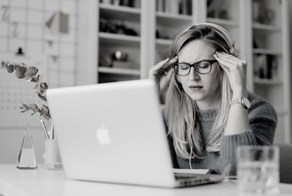 Woman holding her head stressed or anxious in front of a laptop