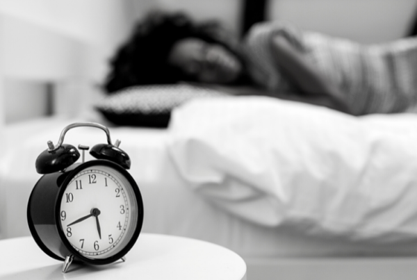 A woman sleeping with an alarm clock next to her