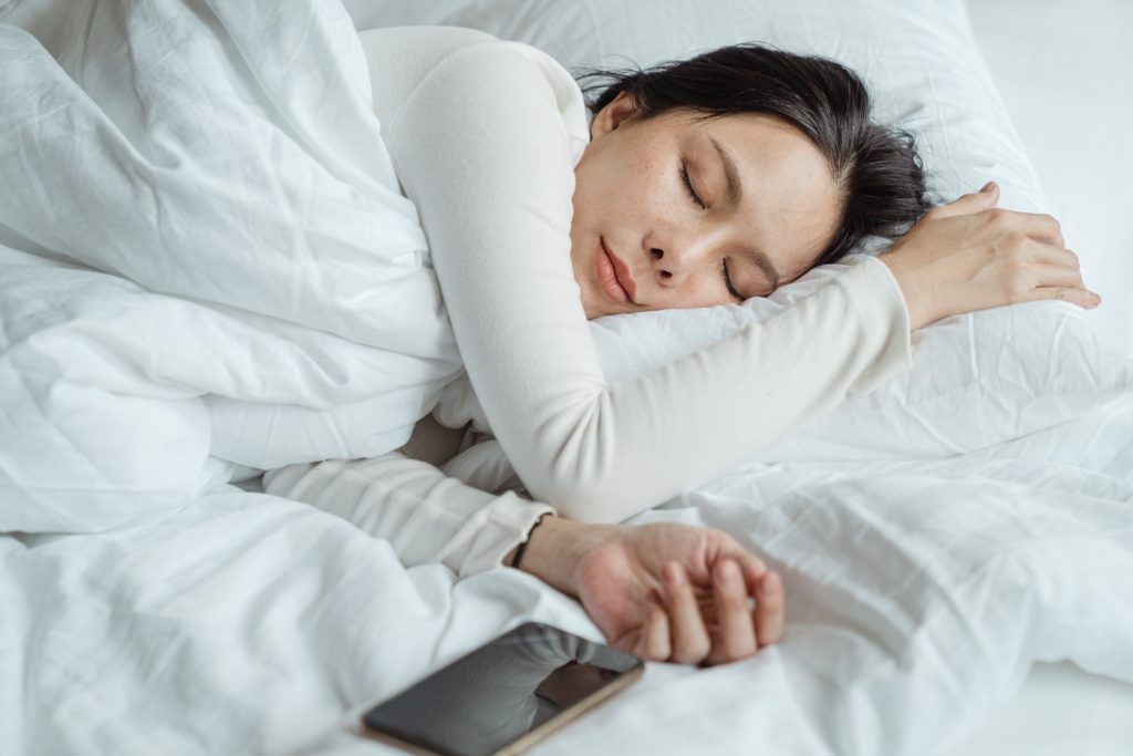 A woman sleeping with her phone next to her tracking her sleep