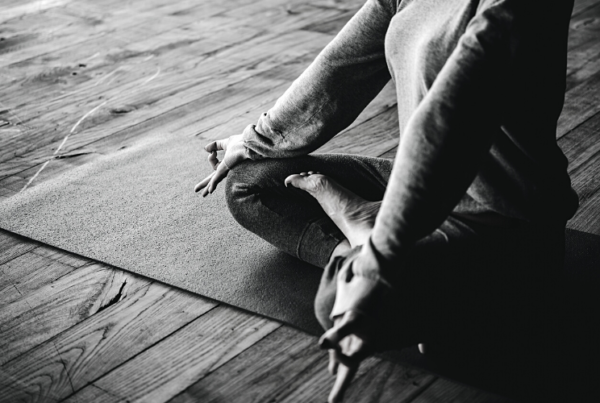 A woman sat on a mat on the floor taking part in yoga - Wellness Program