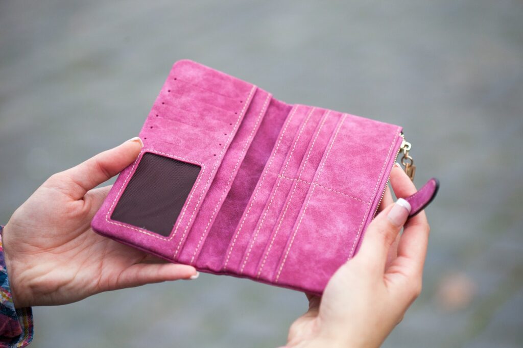 image of an epty pink wallet being held open for a blog by Wellspace on surviving until payday