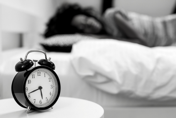 Image of a person sleeping next to an alarm clock for blog by Wellspace on improving sleep